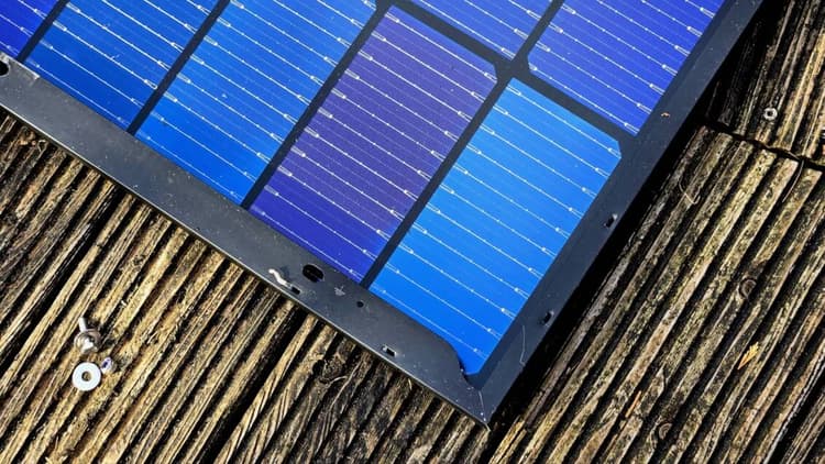 Blau schimmerndes Solarmodul liegt auf dem Boden