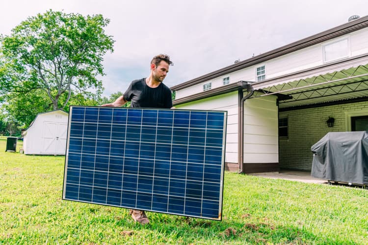 Mann stellt Solarmodul auf - hochkant oder quer? (Bild: iStock / Jeremy Poland)